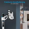 A cordless vacuum cleaner and its charging wall mount are displayed against a dark gray wall, with a living room scene visible in the background. Produktbild-Vorschau