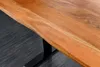 A close-up shot of a wooden table with a live edge, supported by a black metal leg. Produktbild-Vorschau