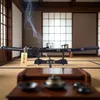 A katana sword displayed on a stand in a traditional Japanese room with shoji screens and tatami mats. Smoke is rising from an incense burner. Produktbild-Vorschau