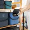 A person is placing papers into a blue storage bin on a shelf. Produktbild-Vorschau