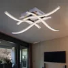 A modern ceiling light fixture with curved LED elements, mounted on a ceiling in a room with a television and a large window. Produktbild-Vorschau