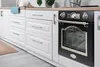 A modern kitchen with white cabinets and a black oven. Produktbild-Vorschau