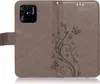 A brown flip case for a smartphone with a floral and butterfly embossed design. Produktbild-Vorschau