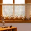A close-up view of a lace bistro curtain with tassels hanging over a wooden window frame, with a decorative sculpture and pinecones on a wooden table in the foreground. Anteprima dell’immagine prodotto