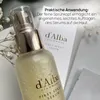 A close-up shot of a d'Alba piedmont First Spray Serum bottle, with text overlay describing its practical application. Produktbild-Vorschau