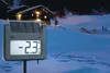 A digital thermometer in a snowy outdoor setting at night, with a lit cabin in the background. Produktbild-Vorschau