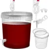 A transparent fermentation bucket filled with red liquid, along with various accessories for winemaking. Anteprima dell’immagine prodotto