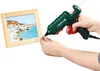 A person is using a hot glue gun to decorate a picture frame with small embellishments. Produktbild-Vorschau