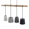 A pendant light fixture with a natural wood beam and four fabric lampshades in different colors. Produktbild-Vorschau