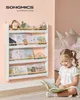A young girl is reading a book in front of a white and natural wood bookshelf filled with children's books and toys. Produktbild-Vorschau