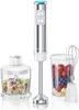 A silver and white immersion blender set with accessories, including a chopper and a whisk, is displayed against a white background. The blender is shown with a container of chopped vegetables and another container filled with berries. Produktbild-Vorschau