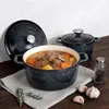 A set of cast iron pots with a stew inside, placed on a wooden table with some garlic and rosemary. Produktbild-Vorschau
