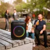 People enjoying themselves outdoors with a speaker playing music. Produktbild-Vorschau