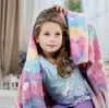 A young girl is wrapped in a colorful blanket with stars and hearts, looking up. Náhľad obrázku produktu