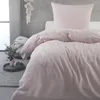 A bed with pink bedding in a room with a concrete wall. Produktbild-Vorschau