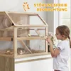 A young girl is looking at a wooden hamster cage with two levels, which is placed on a kitchen counter. Náhled obrázku produktu