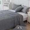 A neatly made bed with a gray blanket and pillows. Produktbild-Vorschau