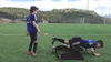 Two boys on a soccer field, one doing an exercise with a ball and a portable goal. Produktbild-Vorschau