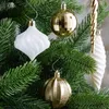 Close-up view of various Christmas tree ornaments, including gold and white baubles, hanging on a green Christmas tree. Náhľad obrázku produktu