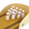 A close-up shot of a miniature bowling set on a wooden lane. Produktbild-Vorschau