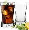 Two glasses, one filled with a dark beverage and ice, the other empty, with garnishes of lemon and rosemary in the foreground. Podgląd zdjęcia produktu