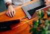 A person using a laptop and external storage device on a wooden desk. Náhľad obrázku produktu