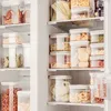 A refrigerator interior filled with clear plastic food storage containers. Produktbild-Vorschau