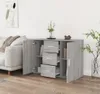 A grey sideboard with drawers and doors is shown in a living room setting next to a sofa. Voir les images du produit