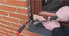 A person is using tools to install or adjust something near a brick wall and a window frame. Produktbild-Vorschau
