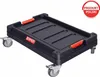A black transport trolley with red handles and silver wheels, shown from a diagonal angle against a white background. A red and white circular badge with text is in the top right corner. Náhľad obrázku produktu