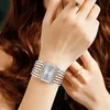 A close-up shot of a woman's wrist wearing a silver watch and rings. Produktbild-Vorschau