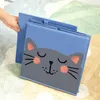 A hand is holding a blue storage box with a cat face design on it, placed on a colorful rug. Náhled obrázku produktu