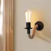 A wall lamp with a light bulb and a rope detail, mounted on a wall next to a curtain. Náhľad obrázku produktu