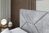 A close-up view of a modern bed's upholstered headboard and a bedside table with a lamp and vase. Produktbild-Vorschau