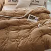 A close-up view of a brown quilted blanket with a floral pattern, laid on a bed with pillows. Produktbild-Vorschau