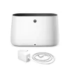 A white humidifier with a black top rim and a small gray circular button on the front, shown with its white power adapter and coiled cord. Produktbild-Vorschau