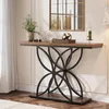 A console table with decorative items is placed against a wall with molding and a mirror above it. A window with sheer curtains is to the left. Náhled obrázku produktu
