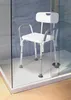 A white shower chair with a backrest and armrests is placed inside a modern shower stall with glass doors and blue tiled walls. Náhled obrázku produktu
