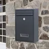 A dark gray mailbox mounted on a stone wall next to a window. Podgląd zdjęcia produktu