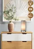 A bedside table with a lamp and a vase with a plant. Produktbild-Vorschau
