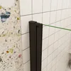 A close-up view of a shower door hinge and frame against a tiled wall and a speckled wall. Produktbild-Vorschau