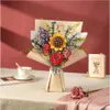 A bouquet of artificial flowers in a vase, placed on a table with a cup and saucer and a small book. Produktbild-Vorschau