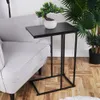 A black side table with a potted plant on top, placed next to a gray armchair. Podgląd zdjęcia produktu