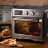 A kitchen counter with an air fryer oven, roasted chicken, and pizza. Podgląd zdjęcia produktu