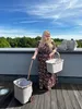 A woman stands on a wooden deck with a shopping cart and basket. Produktbild-Vorschau