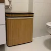 A bamboo laundry basket with a lid and a towel hanging on a cabinet next to it, in a bathroom setting. Produktbild-Vorschau