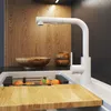 A modern kitchen sink area with a white faucet, wooden backsplash, and a cutting board with fruit. Anteprima dell’immagine prodotto