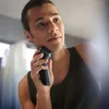 A man is shaving his face with an electric shaver. Podgląd zdjęcia produktu