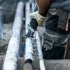 A construction worker is using a reciprocating saw to cut through pipes. Voir les images du produit