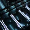 Close-up view of gas burners on a grill, with blue flames visible. Produktbild-Vorschau